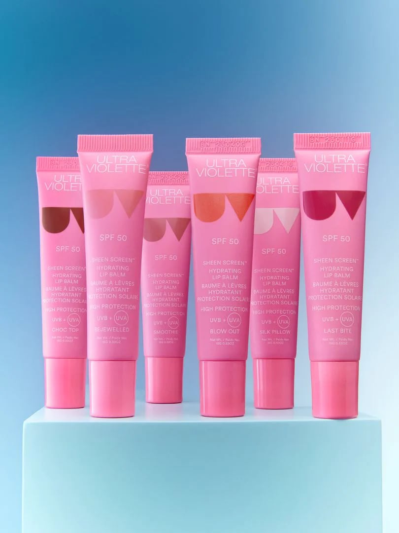 Fünf rosa Tuben Ultra Violette Sheen Screen SPF 50 Lippenbalsam auf blauem Hintergrund.