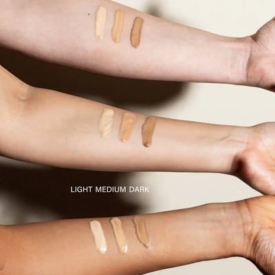 Drei Arme mit verschiedenen Hauttönen zeigen drei Farbtöne von BB-Serum: hell, mittel und dunkel.