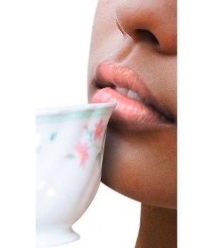 Nahaufnahme von Lippen einer Person, die eine Tasse mit Blumenmuster hält.