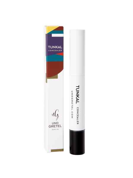 Tunkal Concealer von Und Gretel Berlin, weiße Verpackung mit schwarzem Deckel, bunte Box im Hintergrund.