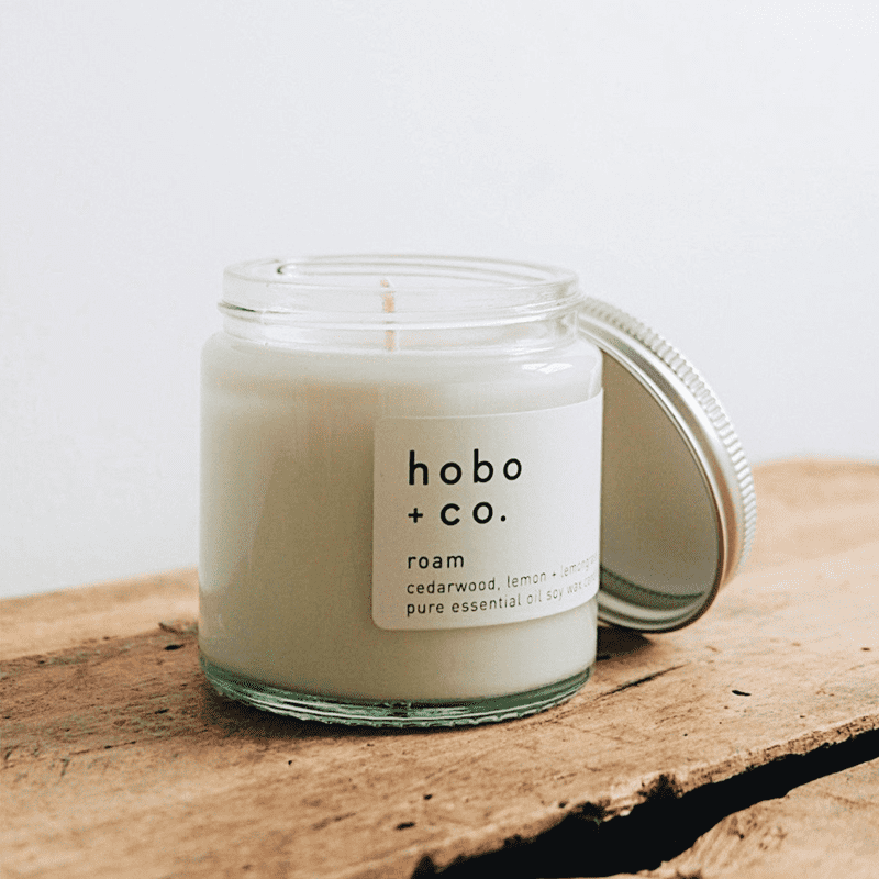 Eine geöffnete Duftkerze von hobo + co. auf einem rustikalen Holztisch.